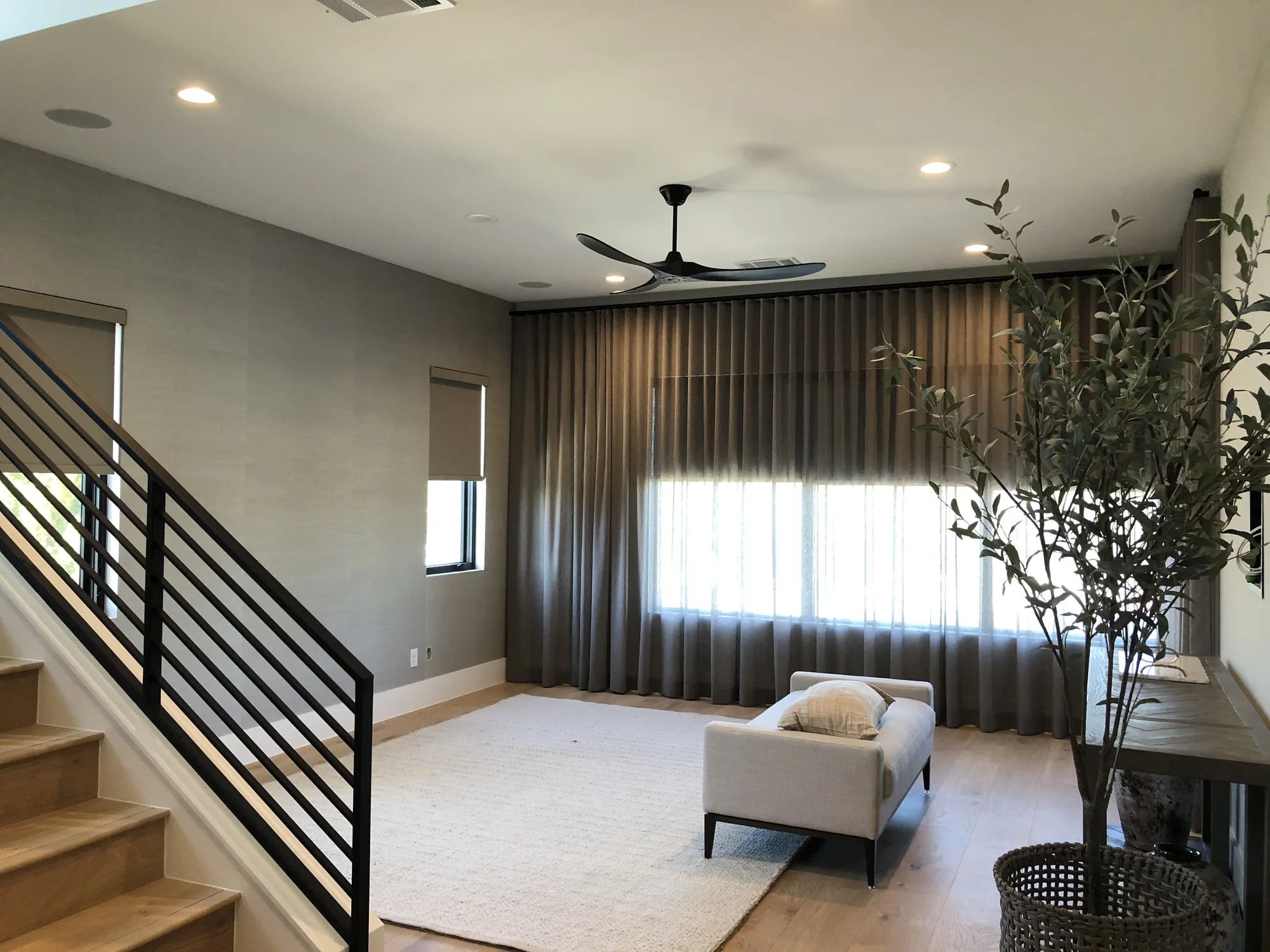 Finished living room with an open staircase and a slatted feature wall