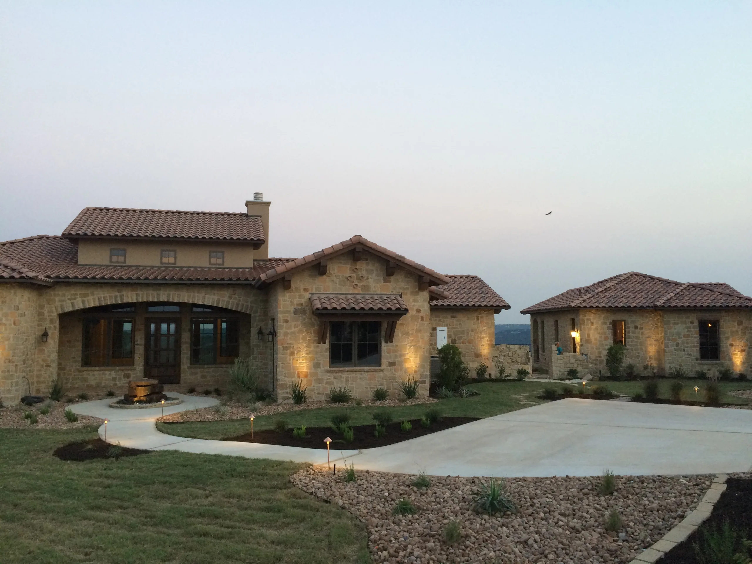Stone ranch home and guest quarters at dusk
