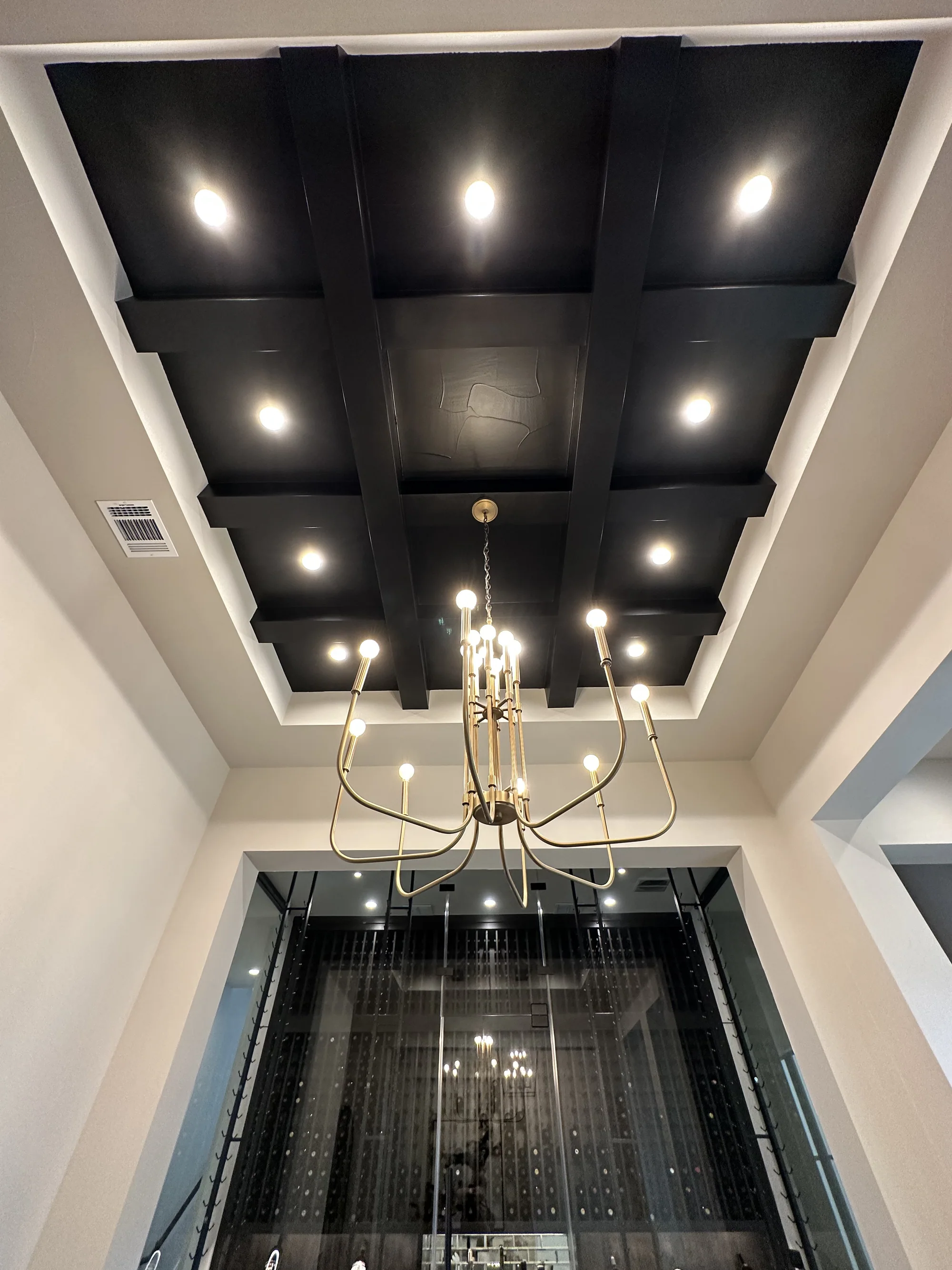 Entry hall with a dark coffered ceiling and sculptural chandelier
