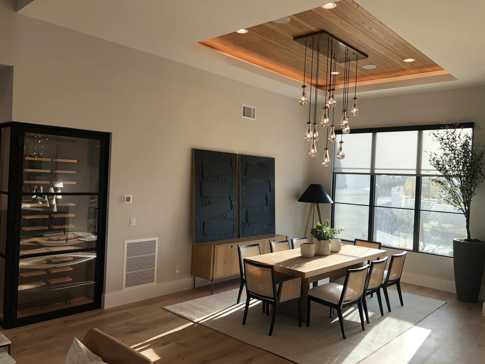 Dining room with a glass wine display, layered ceiling lighting, and views outdoors