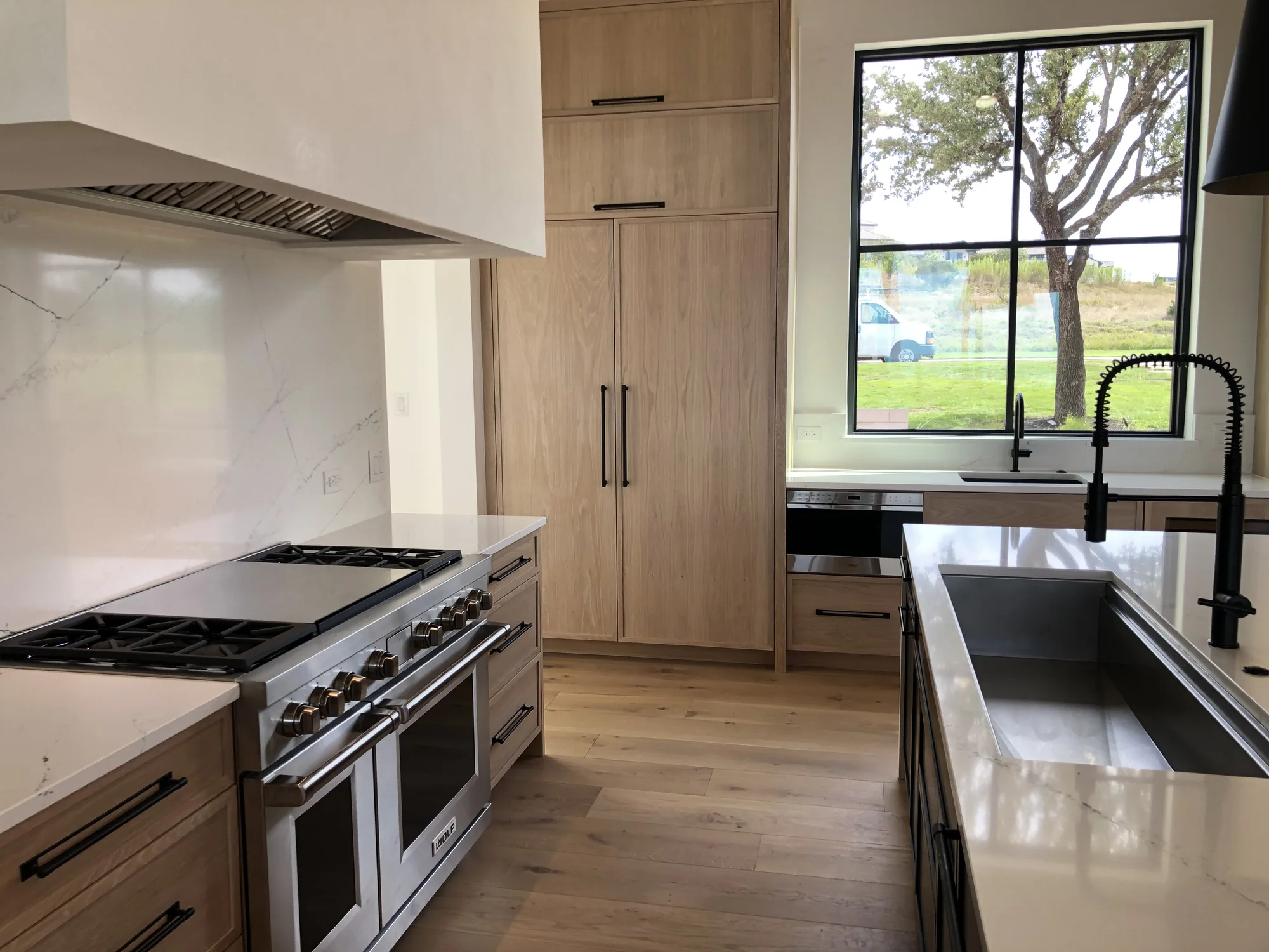 Oak kitchen cabinetry with a professional range and a window overlooking the garden