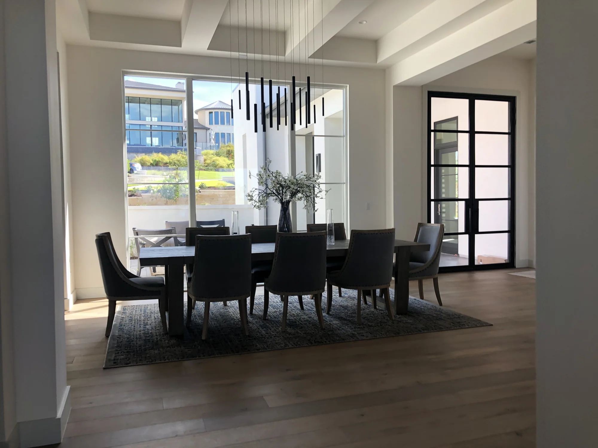 Dining room beneath exposed white beams with a black sculptural chandelier
