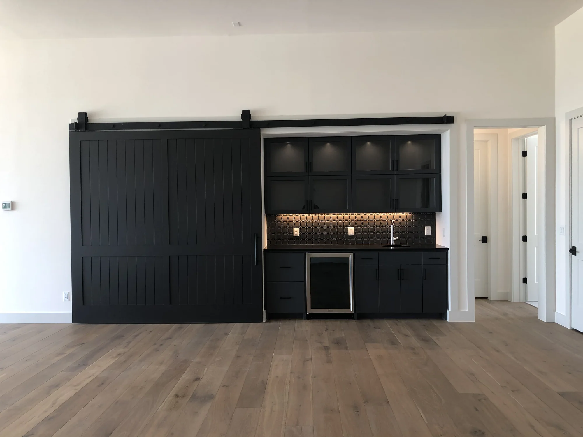 Concealed bar cabinetry behind a black sliding barn door