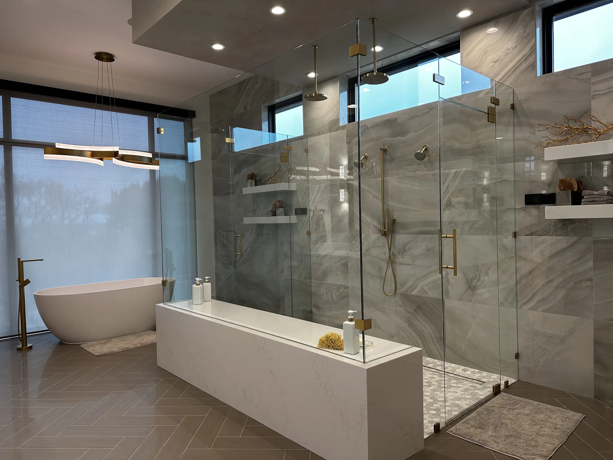 Freestanding soaking tub beside a glass-enclosed marble shower