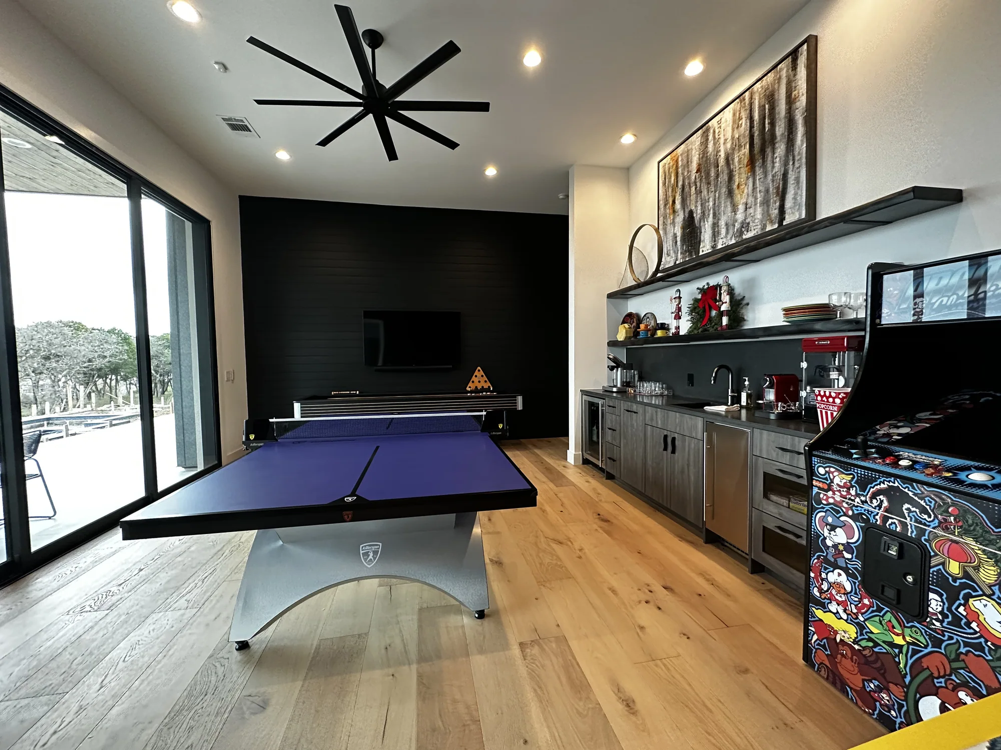 Game room with a pool table, arcade machines, and sliding doors to the terrace