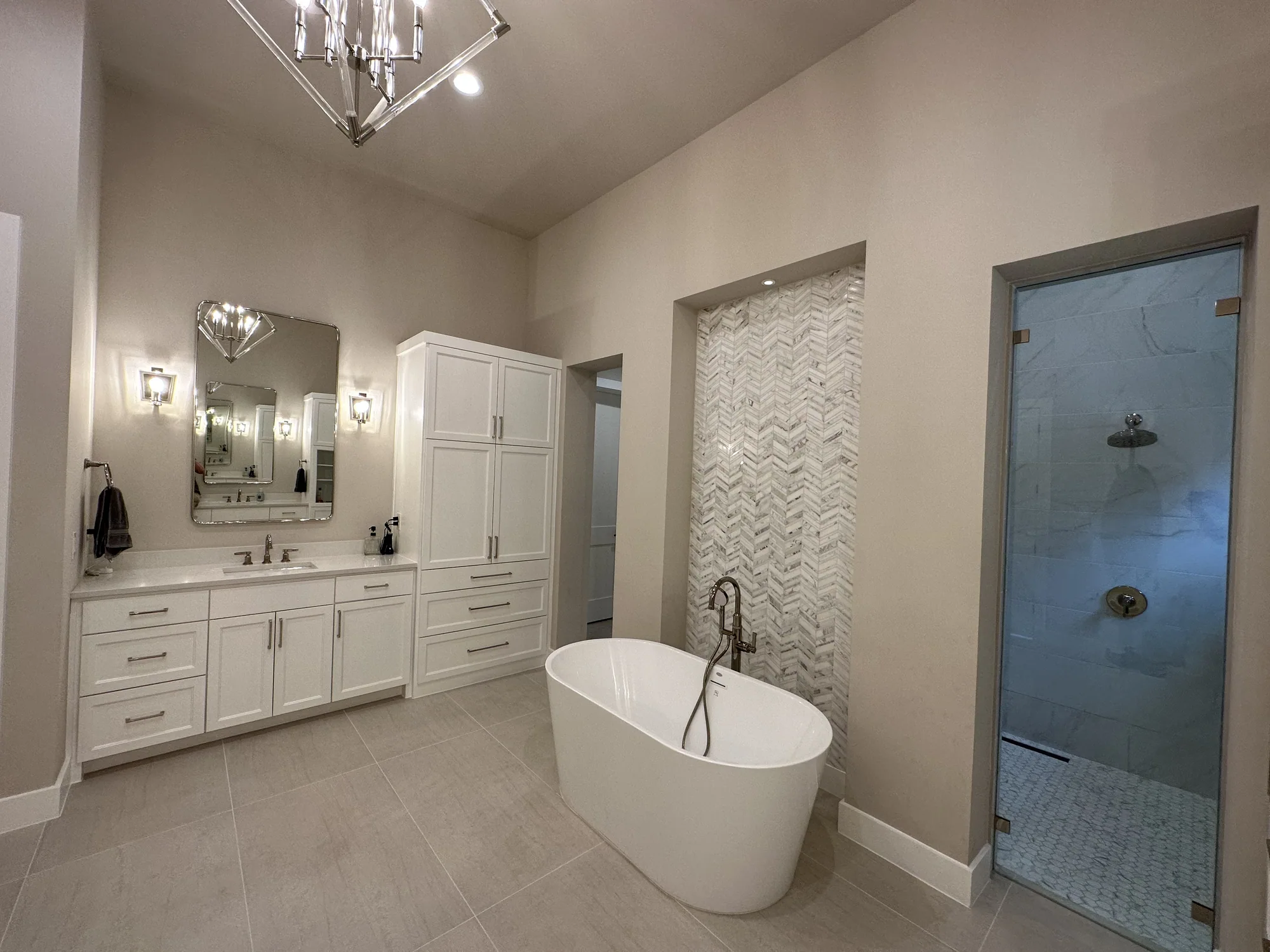 Light-filled primary bathroom with a freestanding tub and fitted white cabinetry