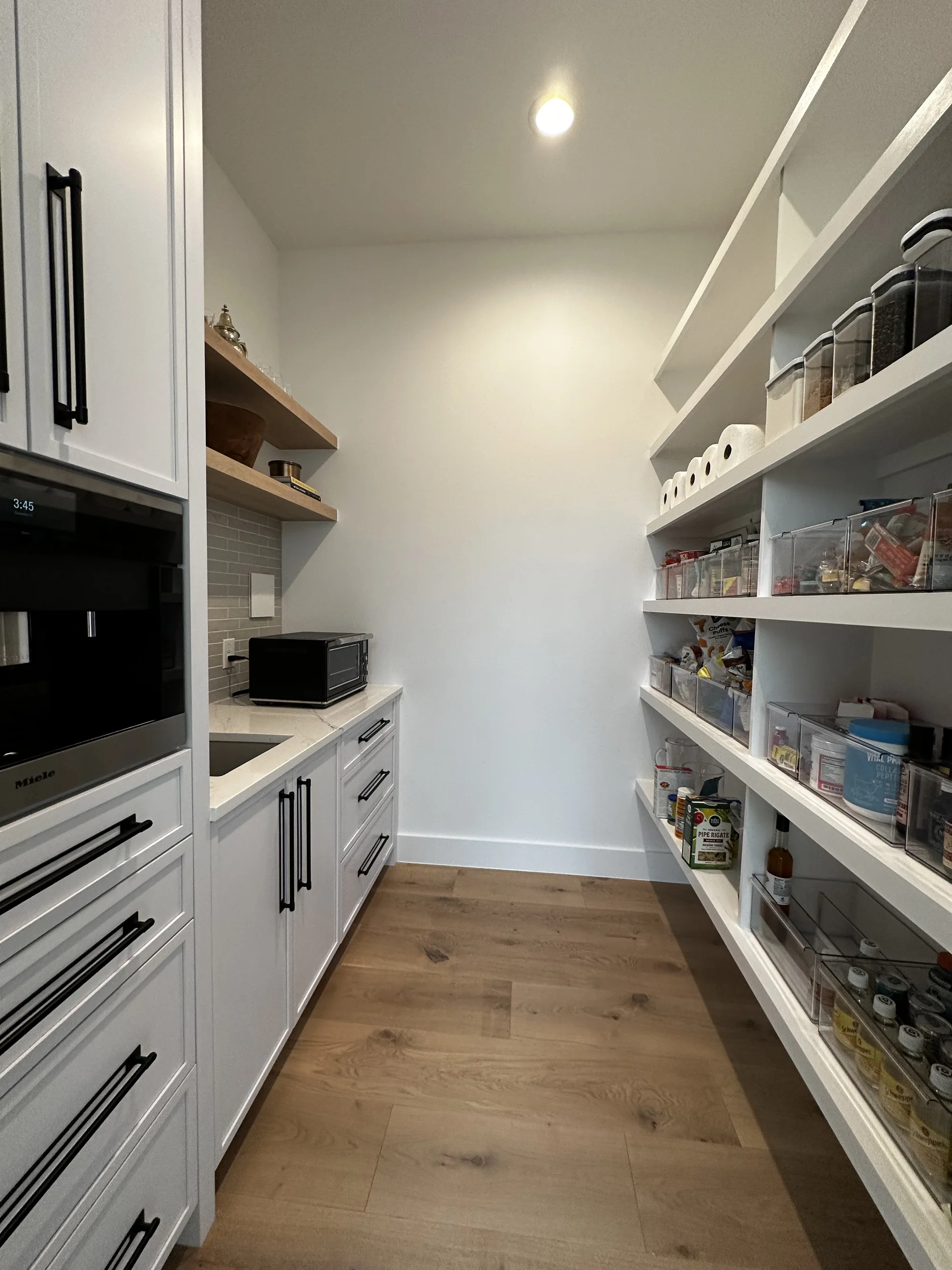 Walk-in pantry with floor-to-ceiling shelving and integrated appliances
