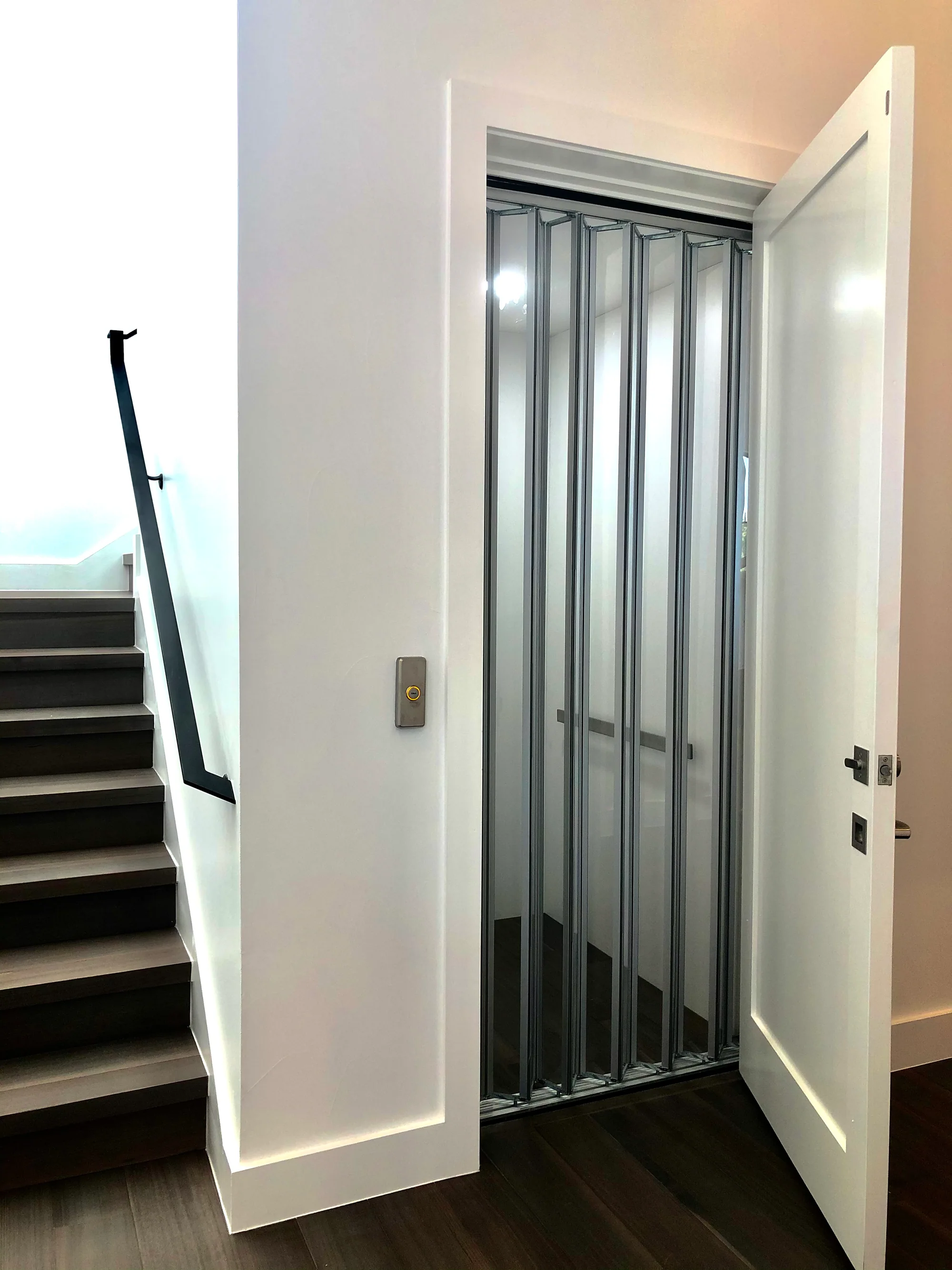 Residential elevator entrance beside a staircase