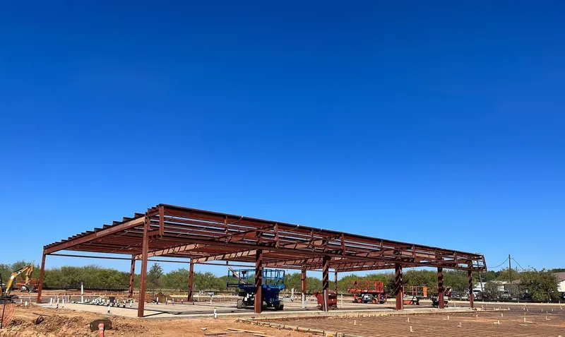 A large metal structure is being built in the middle of a dirt field.