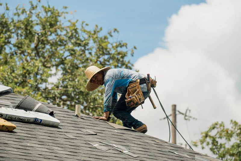 Roofer hand nailing shingles closeup