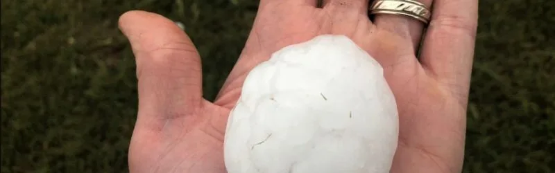 Hand holding a baseball-sized hailstone after a severe Central Texas hailstorm